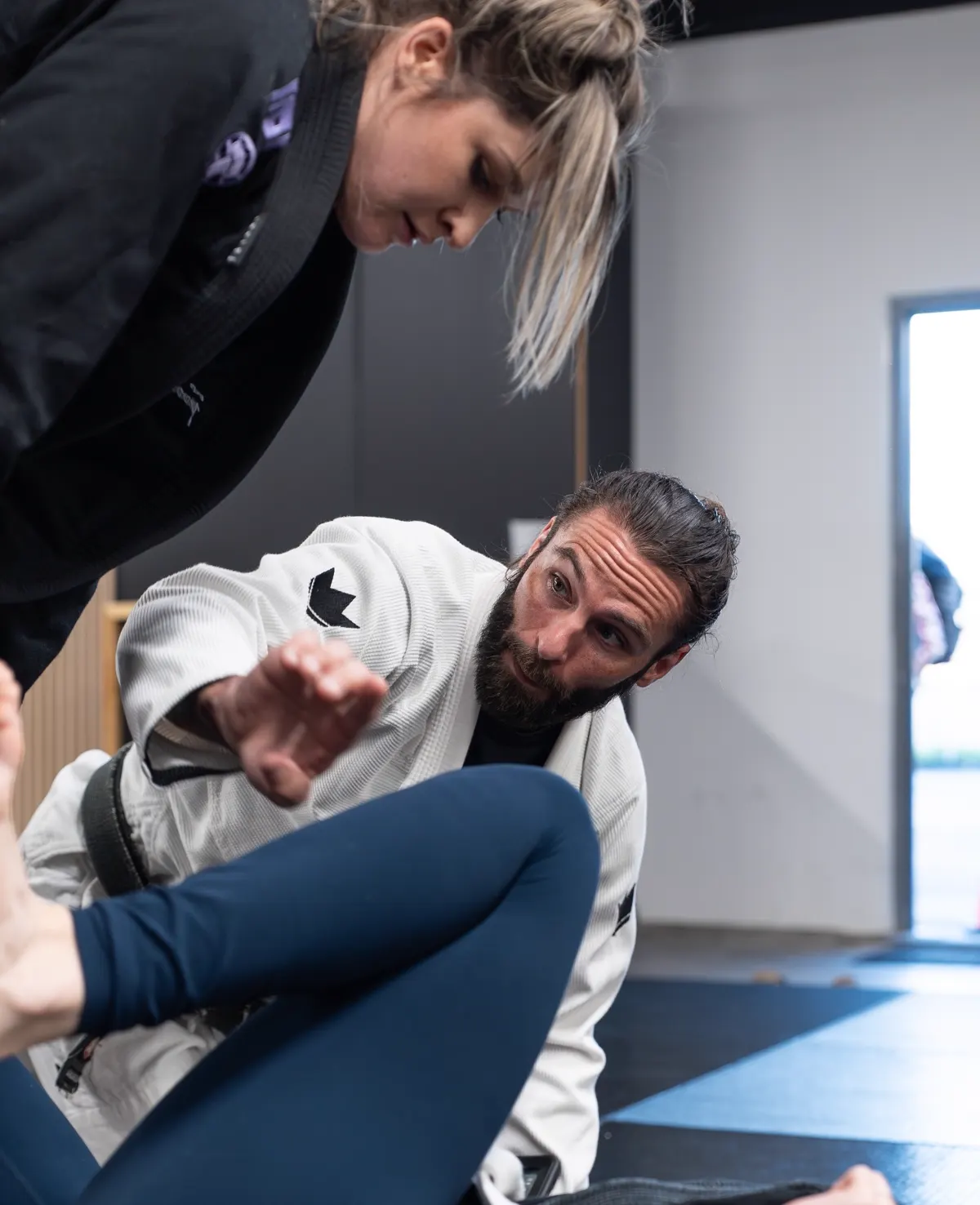 Logic Jiu Jitsu coach guiding a beginner through a technique on the mat