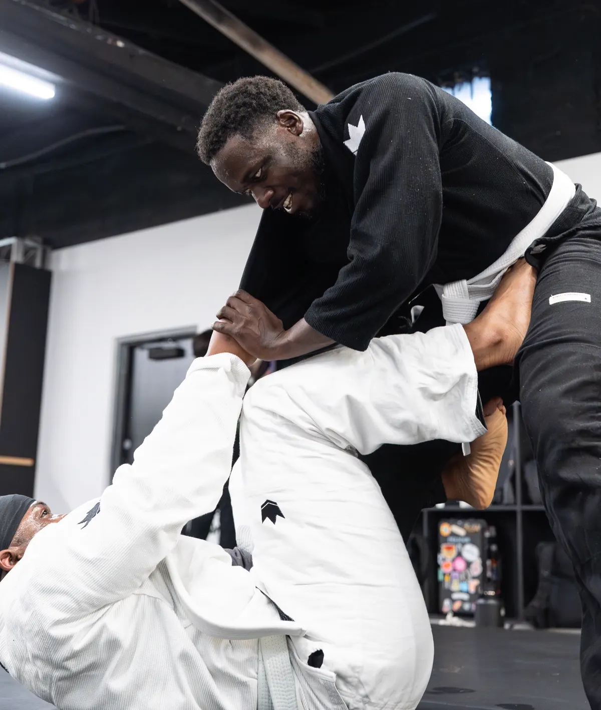 Logic Jiu Jitsu member smiling mid-roll during a beginner class